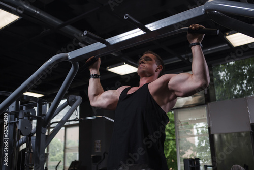 Strong muscular man doing pull ups at the gym