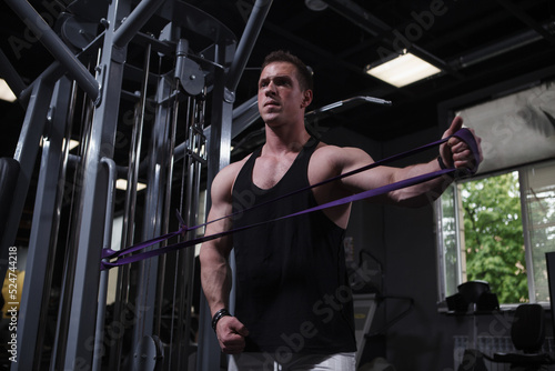Strong muscular male athlete training with resistance band