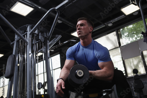 Low angle shot of a bodybuilder doing bicep curls with a dumbbell