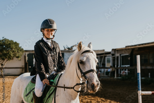 portrait of a 12 year old girl riding a white pony in competition gear