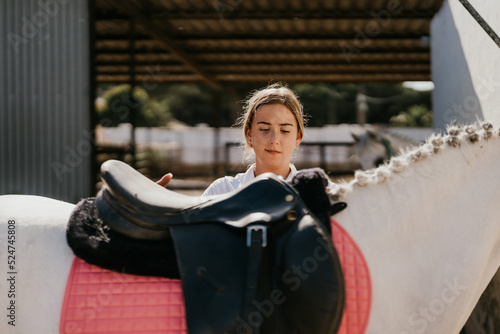 adolescent placing a saddle on a white horse © Samuel Perales