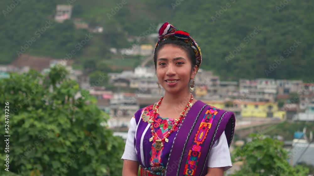 Person in a field. Beautiful Hispanic woman looking at the camera with the mountains and town in the background. Person in a field. Beautiful Hispanic woman looking at the camera with the mountains and town in the background.