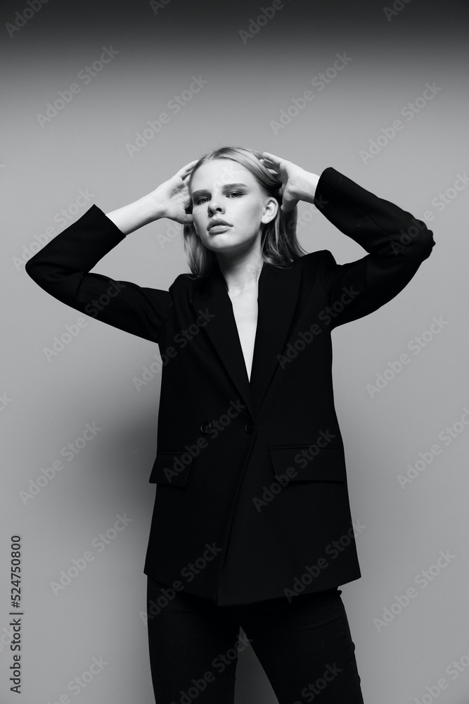 An elegant stylish girl tucks her hair behind her ears and raises her hands up. A stylish lady in a suit poses in the studio. The concept of style for brands An elegant stylish girl tucks her hair behind her ears and raises her hands up. A stylish lady in a suit poses in the studio. The concept of style for brands