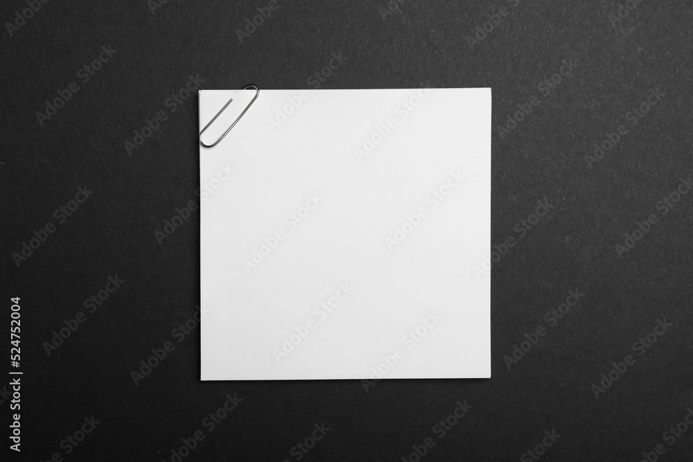 Sheet of paper with clip on black background, top view Sheet of paper with clip on black background, top view