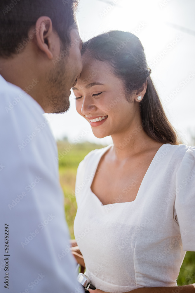 man kissing girlfriend on forehead in the street in the countryside. Romantic young man giving a kiss to his woman in the city street. Loving young couple man kissing girlfriend on forehead in the street in the countryside. Romantic young man giving a kiss to his woman in the city street. Loving young couple