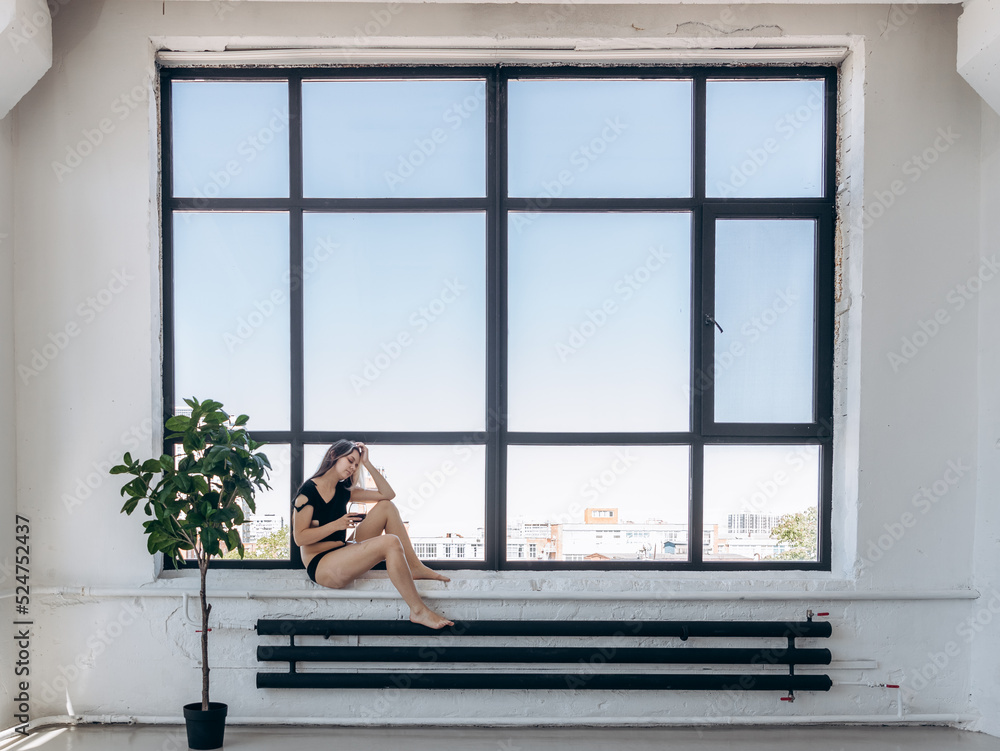 a girl in a torn T-shirt drinks wine in a spacious building a girl in a torn T-shirt drinks wine in a spacious building