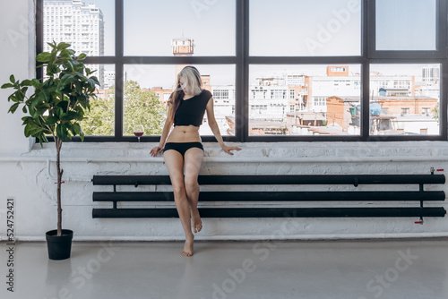 a girl in a torn T-shirt drinks wine in a spacious building