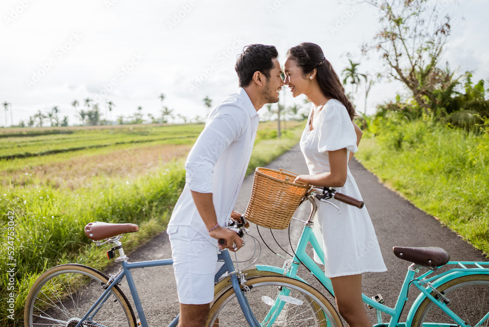 romantic young couple put their head together while riding bicycle outdoor romantic young couple put their head together while riding bicycle outdoor