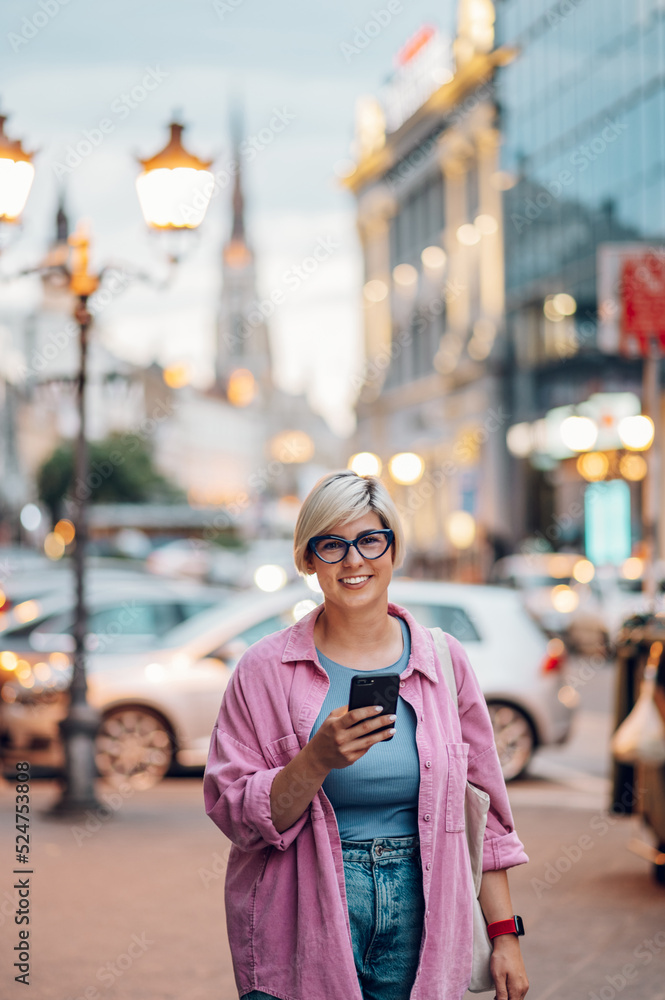 Plus size woman with pixie hair using smartphone in the city street.