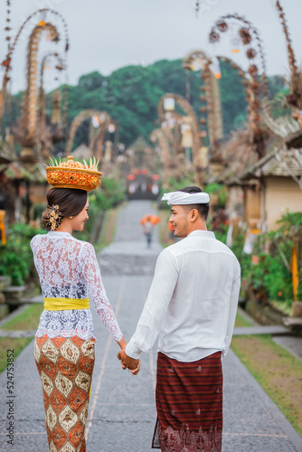 balinese couple portrait from behind while walking in penglipuran heritage village photo