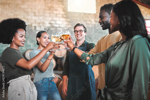 Friends wine tasting, giving cheers and toast celebrate with champagne glasses in cellar, distillery and brewery. Group of happy, diversity and smile people for social event, hangout and winery tour photo