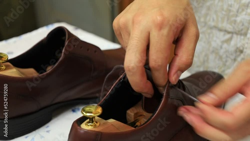 靴磨き作業　職人　靴ひもを通す