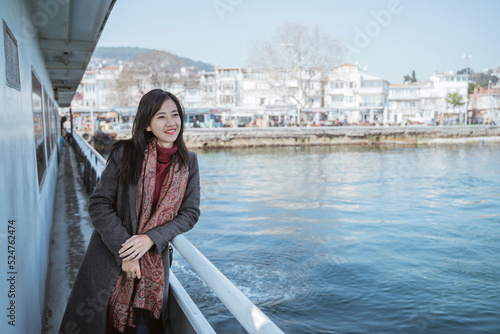 portrait of woman leaning against the railing of the ferryboat while crossing the sea © Odua Images