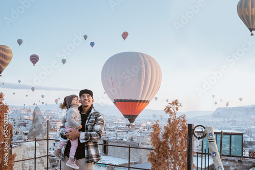 happy family looking at hot air balloon flying around them when visiting cappadocia turkey in winter photo