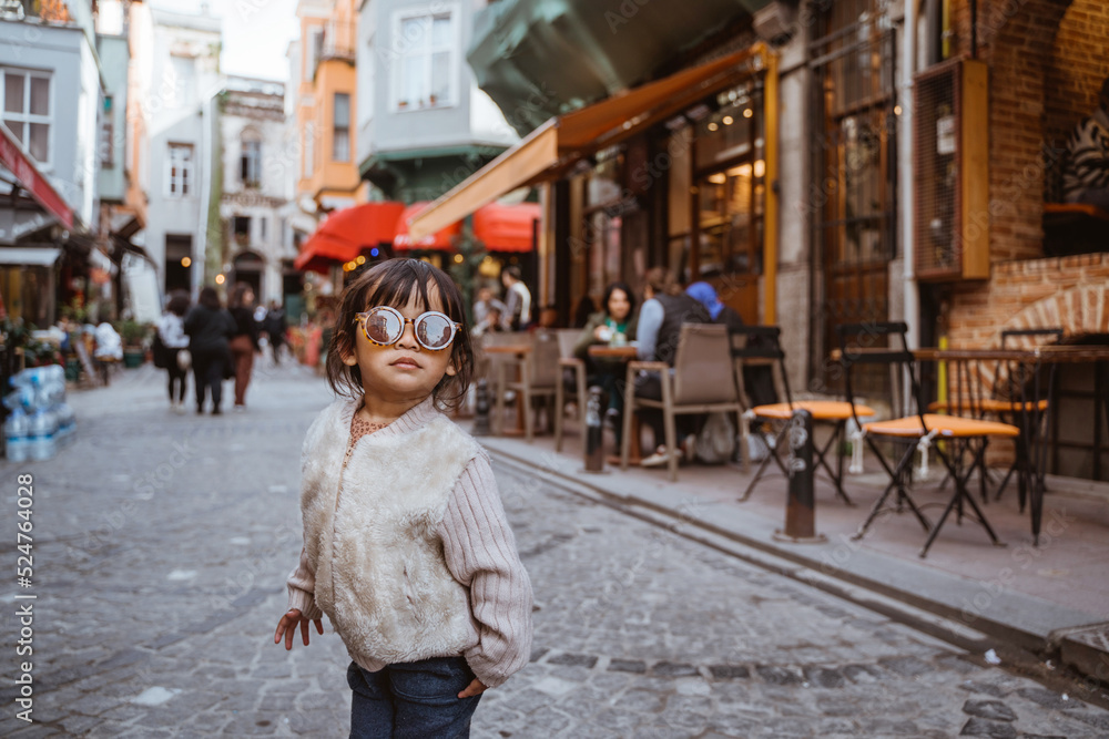 Fototapeta premium cute stylish kid walking around the old town area wearing sunglasses