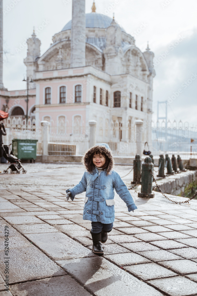 happy kid running around the square in turkey with ortakoy mosque in the background
