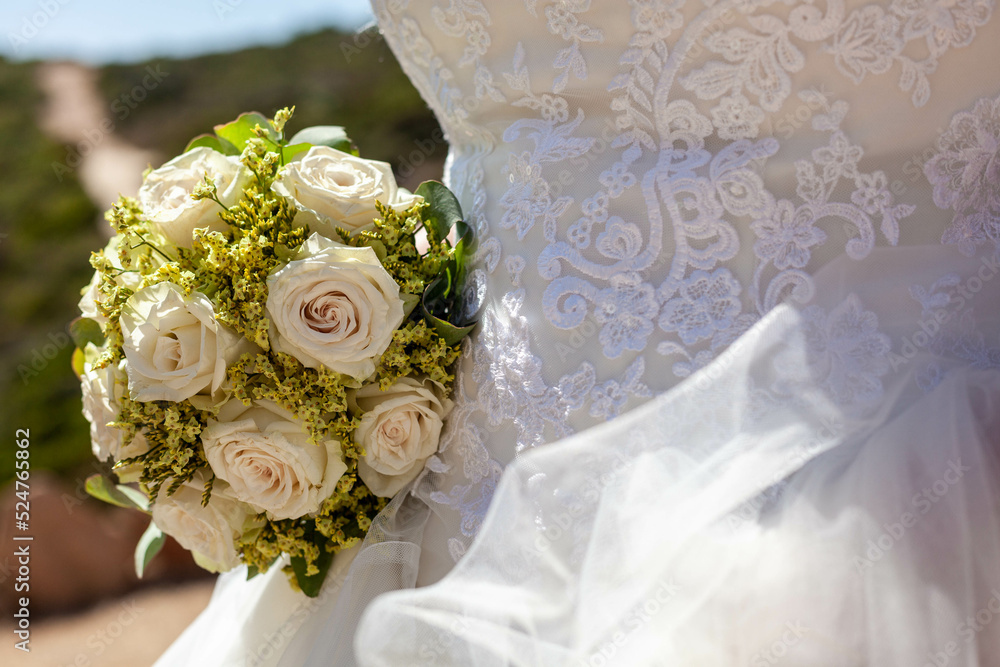 wedding bouquet of flowers and detail of a wedding gown wedding bouquet of flowers and detail of a wedding gown