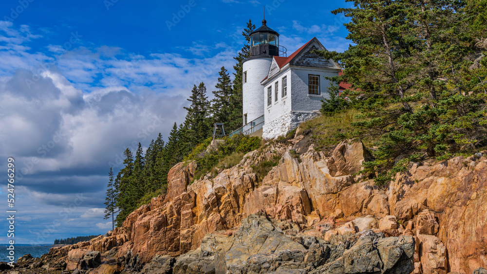 Obraz premium Bass Harbor Head Light - A close-up view of Bass Harbor Head Lighthouse at top of colorful seaside cliff, as stormy clouds building in background. Acadia National Park, Maine, USA.