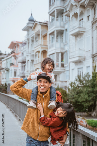 Canvas Print father carrying his daughter on a shoulder while exploring bebek arnavutkoy area