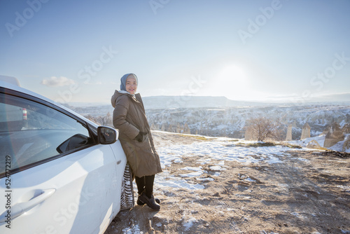 portrait of young asian woman on her adventure going to beautiful hill in cappadocia in winter by her car