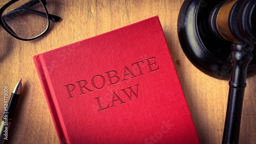 Probate law book on wooden table surrounded with gavel, glasses and pen. Law concept