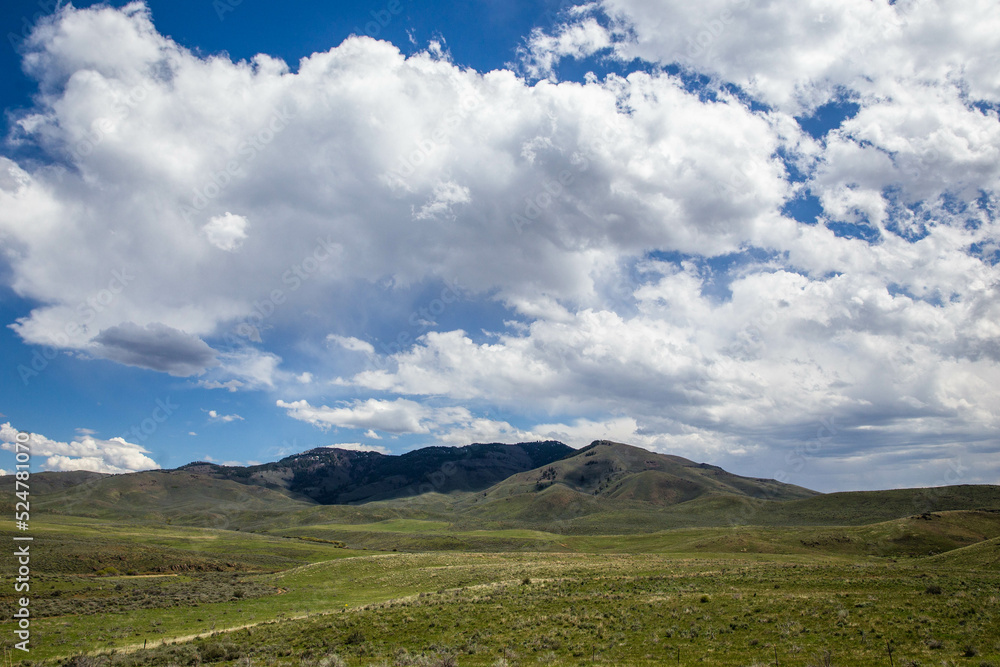 Fototapeta premium Cloudy blue sky over mountain and green valley