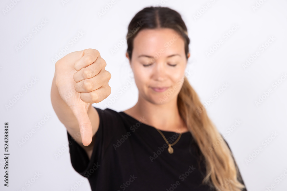 Close-up of mid adult woman showing thumb down. Caucasian woman wearing black blouse making dislike gesture. Disapproval or rejection concept Close-up of mid adult woman showing thumb down. Caucasian woman wearing black blouse making dislike gesture. Disapproval or rejection concept