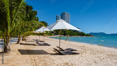 Fototapeta Naklejka Na Ścianę i Meble -  Beach chairs on the beach of Ban Amphur Beach Pattaya Thailand, a beach with beautiful palm trees and a blue ocean in Pattaya Thailand