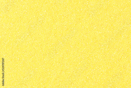 Glitter texture, background in beautiful yellow tone for holiday mood. Sparkling shiny wrapping paper for Christmas holiday seasonal wallpaper decoration, greeting and winter Christmas design element.