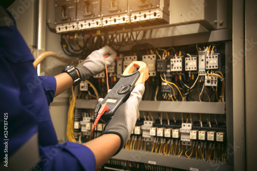 Electricity or electrical maintenance service, Engineer hand holding voltmeter checking electric current voltage at circuit breaker terminal and cable wiring main power load center distribution board.