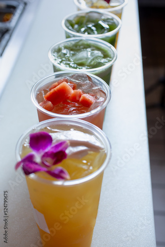 A view of several cups of sugarcane drinks in different rainbow colors.