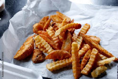 A view of a portion of deep fried crinkle cut french fries.