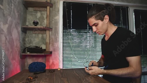 Man makes dreamcatcher in authentic workshop. Artisan in art studio.