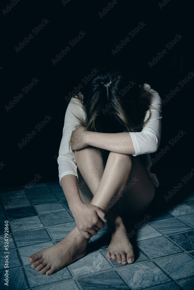 Young person woman sad, stress and loneliness sitting in dark room, Unhappy and crying teenage girl from domestic violence, An adult female expresses feelings of despair, anxiety from harassment. Young person woman sad, stress and loneliness sitting in dark room, Unhappy and crying teenage girl from domestic violence, An adult female expresses feelings of despair, anxiety from harassment.