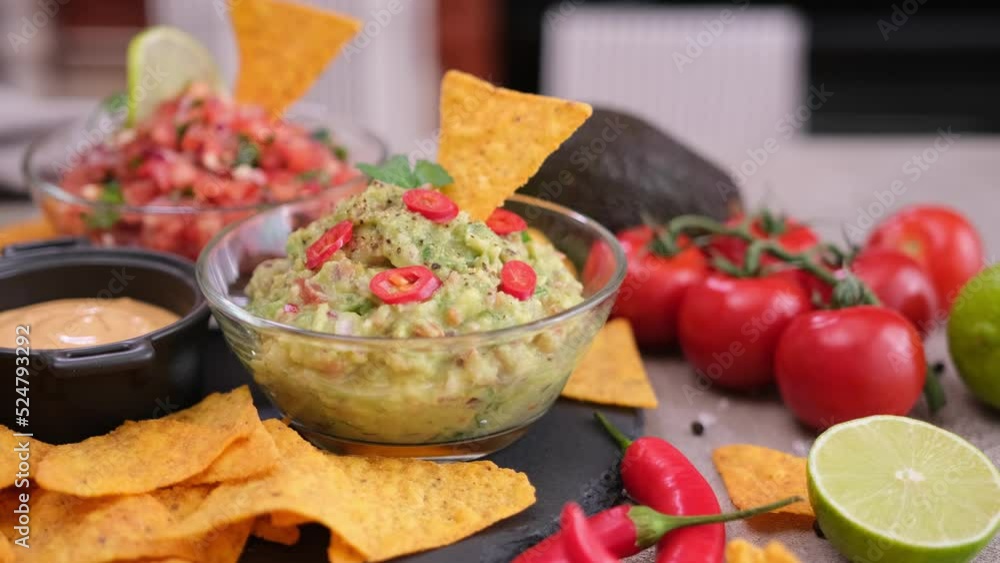 salsa and guacamole dip sauces, nacho chips on stone serving board salsa and guacamole dip sauces, nacho chips on stone serving board