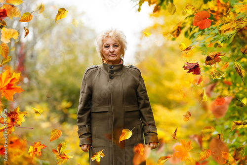 health, charity and valentine's day concept - portrait of smiling senior woman holding red heart over autumn leaves and nature background