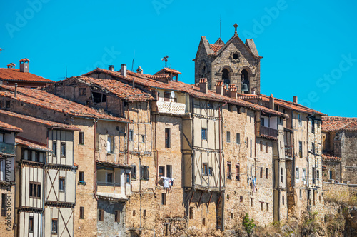 Viejas y antiguas casas colgantes en la villa de Frías con campanario de la iglesia asomando sobre los tejados, provincia de Burgos, España