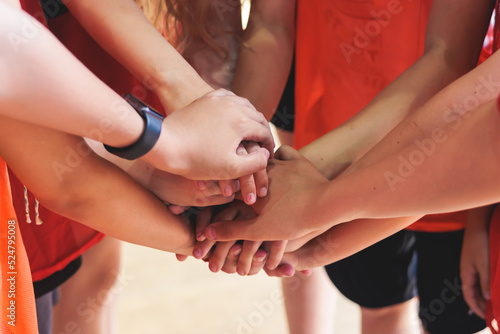 Team of kids children basketball players stacking hands in the court  sports team together holding hands getting ready for the game  playing indoor basketball  team talk with coach  close up of hands