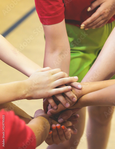 Team of kids children basketball players stacking hands in the court, sports team together holding hands getting ready for the game, playing indoor basketball, team talk with coach, close up of hands