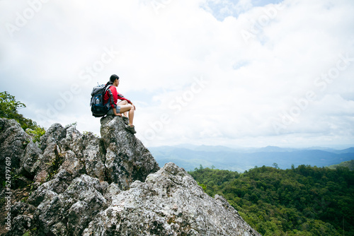 Young person hiking female sitting on top rock, Backpack woman looking at beautiful mountain valley at sunlight in summer, Landscape with sport girl, high hills, forest, sky. Travel and tourism.