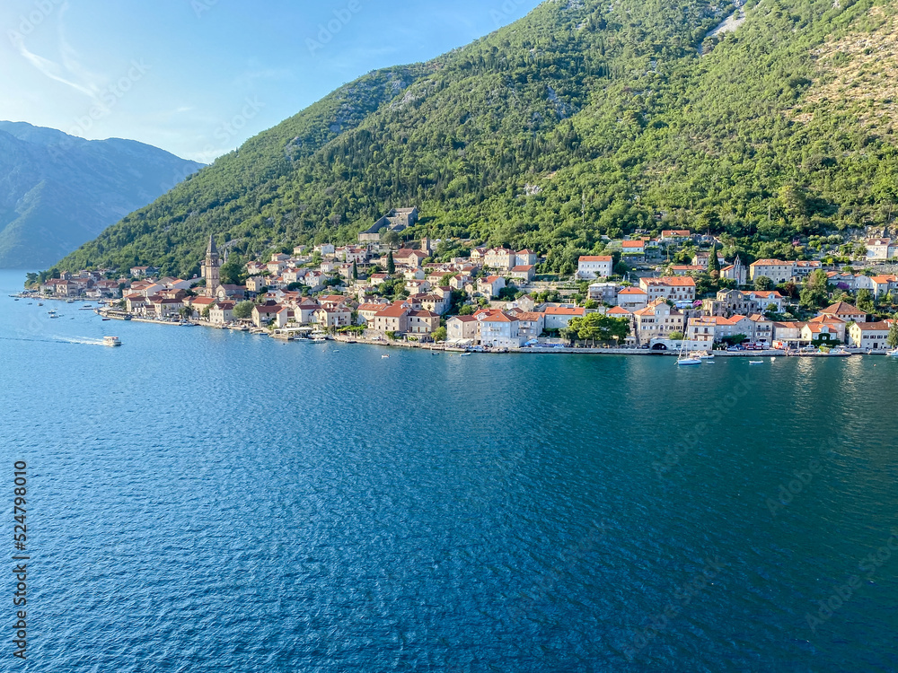 Naklejka premium Kotor, Montenegro - July 18, 2022: Shoreline buildings and cathedrals along the narrow fjord en route to Kotor, Montenegro 