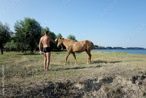 man approaching restless horse on the beach