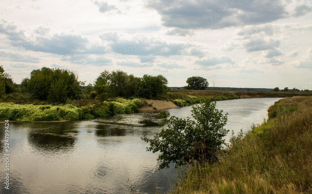 Beautiful landscape - the winding Klyazma river among the banks with green trees and a dramatic cloudy sky on a sunny day in August in the Moscow region