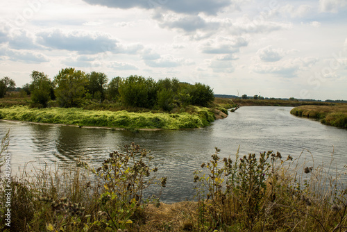 Beautiful landscape - the winding Klyazma river among the banks with green trees and a dramatic cloudy sky on a sunny day in August in the Moscow region