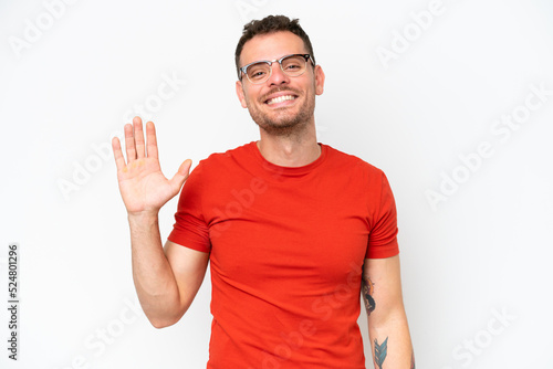 Young caucasian handsome man isolated on white background saluting with hand with happy expression