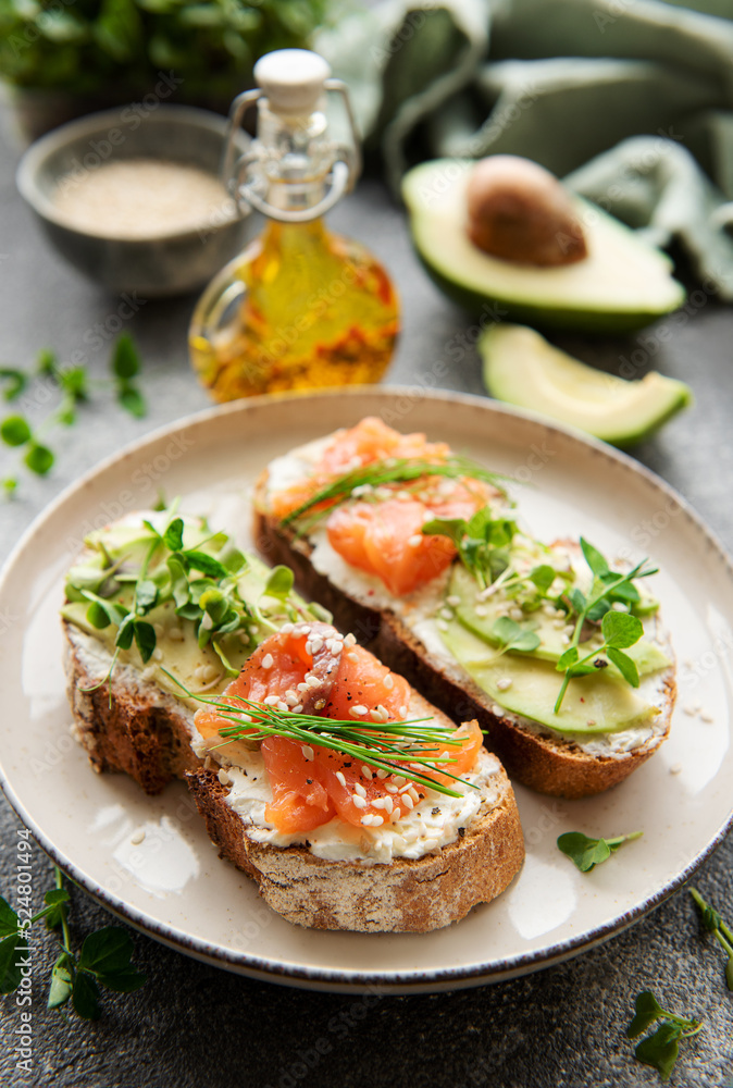 Sandwiches with salted salmon,  avocado and microgreens.
