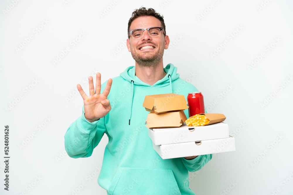 Young caucasian man holding fast food isolated on white background happy and counting four with fingers Young caucasian man holding fast food isolated on white background happy and counting four with fingers
