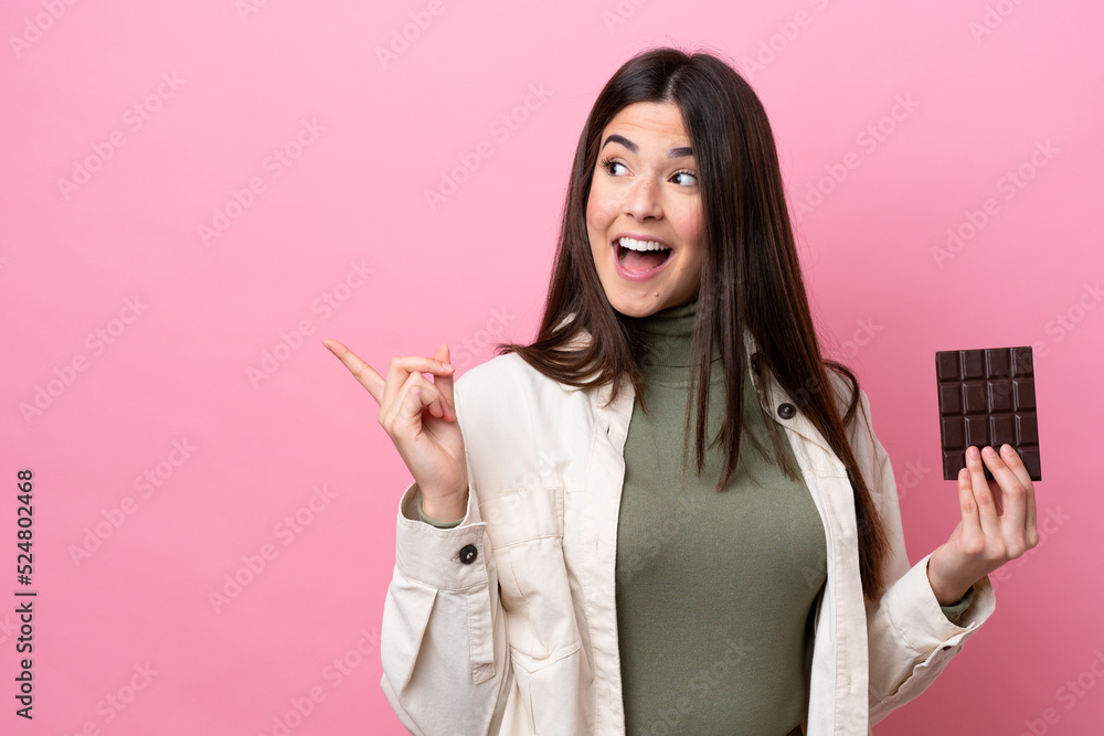 Young Brazilian woman with chocolat isolated on pink background intending to realizes the solution while lifting a finger up Young Brazilian woman with chocolat isolated on pink background intending to realizes the solution while lifting a finger up