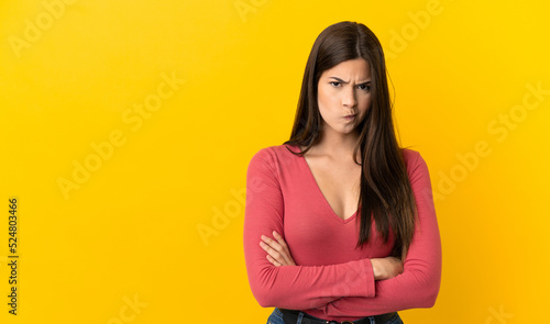 Teenager Brazilian girl over isolated yellow background with unhappy expression