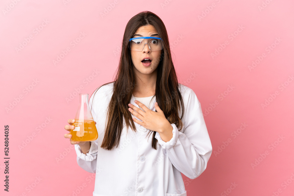 Young scientific girl over isolated pink background surprised and shocked while looking right Young scientific girl over isolated pink background surprised and shocked while looking right